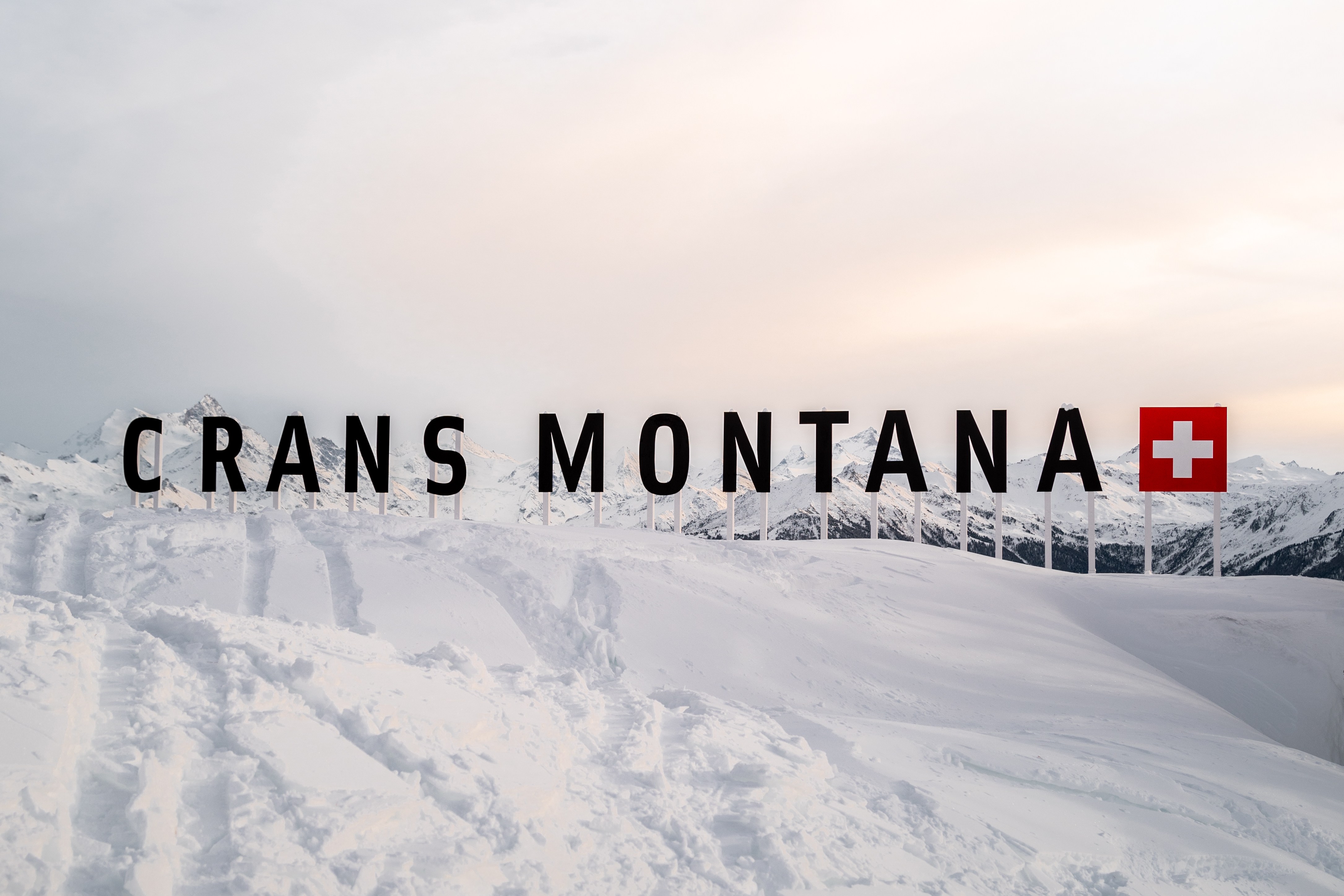 Crans Montana text with flag and snowy mountain